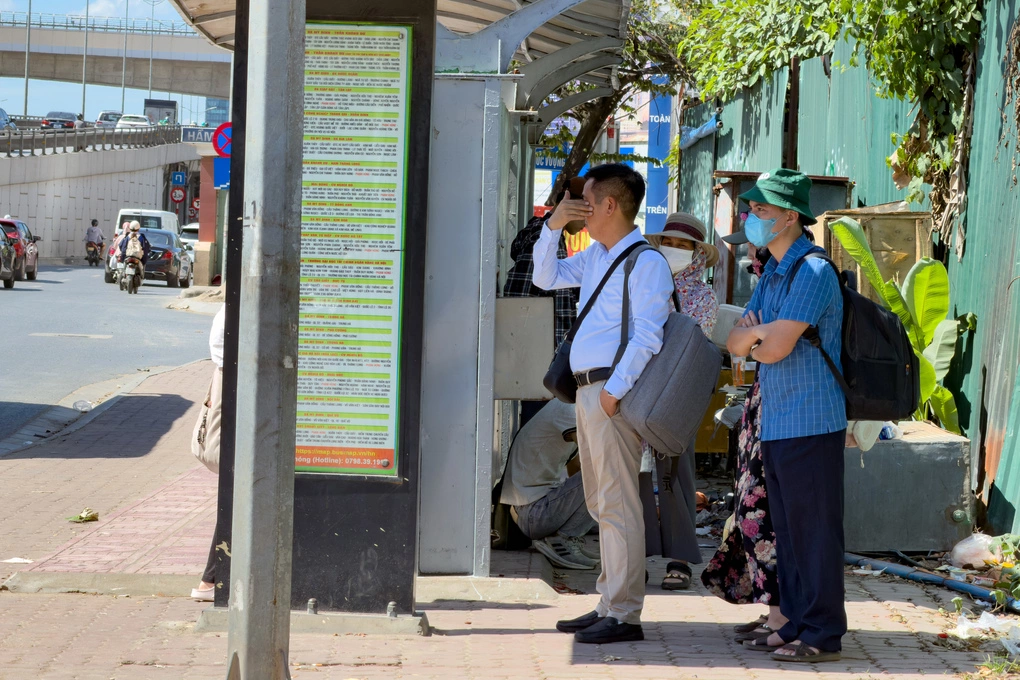 Người dân tránh nắng dưới những mảnh bóng râm ít ỏi trong lúc chờ xe buýt. Ảnh: Tùng Đinh